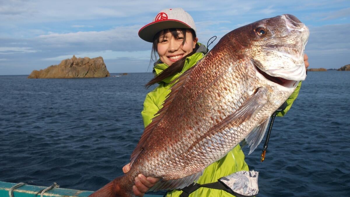 タイラバで釣り上げた大型マダイを掲げる女性アングラー（船上）