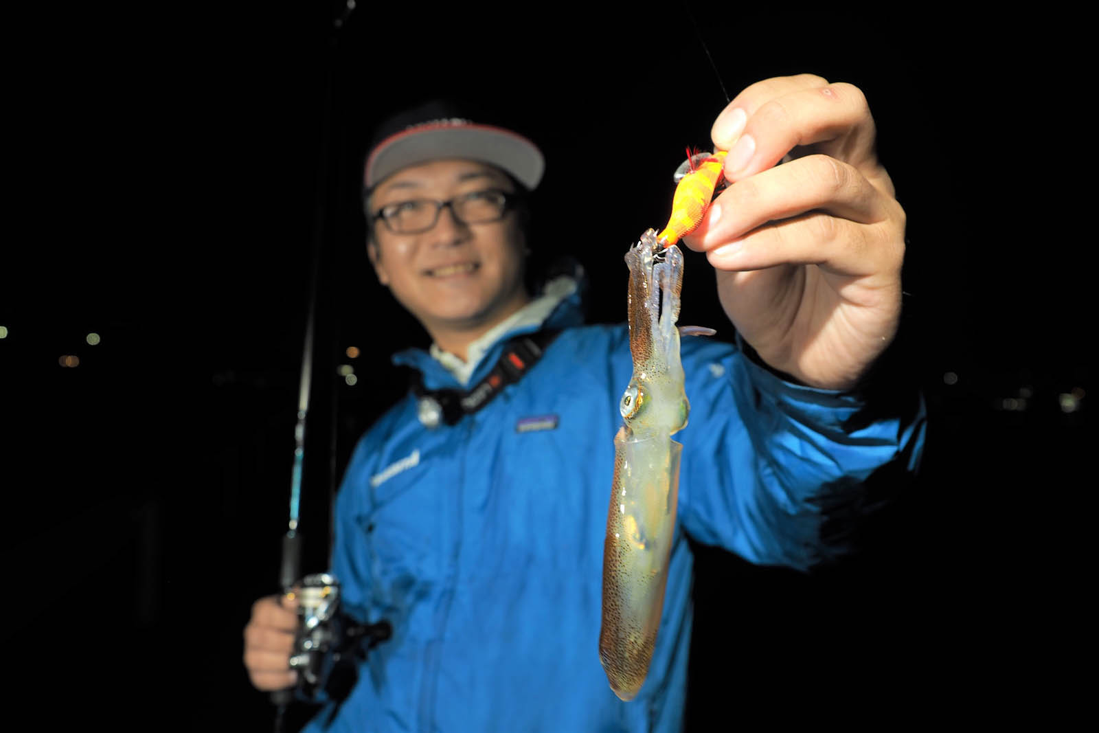 夜の釣り場でヒイカを釣り上げた釣り人