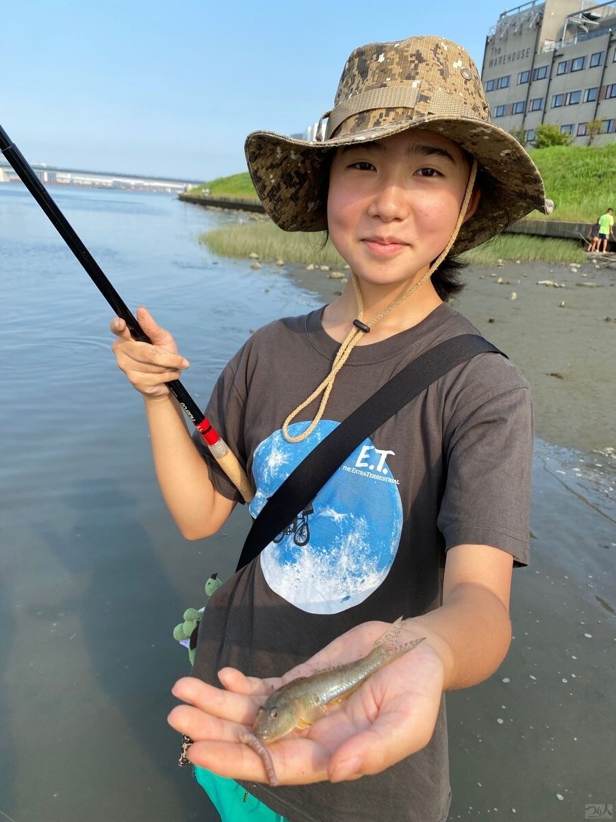 殿町の水際で釣ったハゼを手にする釣り人