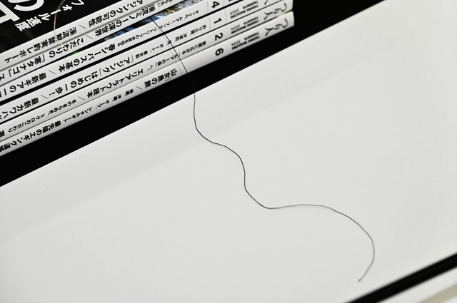 重ねた雑誌にスレッドを挟んで引き出す。こうすることでボビンを手で持たずともテンションを掛けながら巻くことができる。テンションの強さは乗せる雑誌の数で調整する。『つり人』は取り回しのよい大きさでほどよく厚みもあるので使い勝手がよい