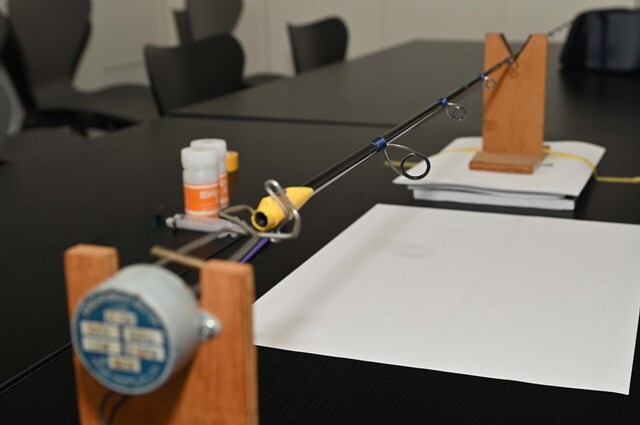 ロッドをフィニッシングモーターにセットする。5～10秒で一回転する低速のモーターで、硬化するまで回転させ続けることでエポキシが偏るのを防ぐアイテム。チャックで挟んで固定するが、傷が入らないようつかむ位置をマスキングテープなどで保護する。台座はマスキングテープなどで机に固定すると硬化中に倒れてしまうトラブルを防げる。また、モーターがついていないほうの台は適当なものでかさ上げして少し高くするとよい（理由は後述）